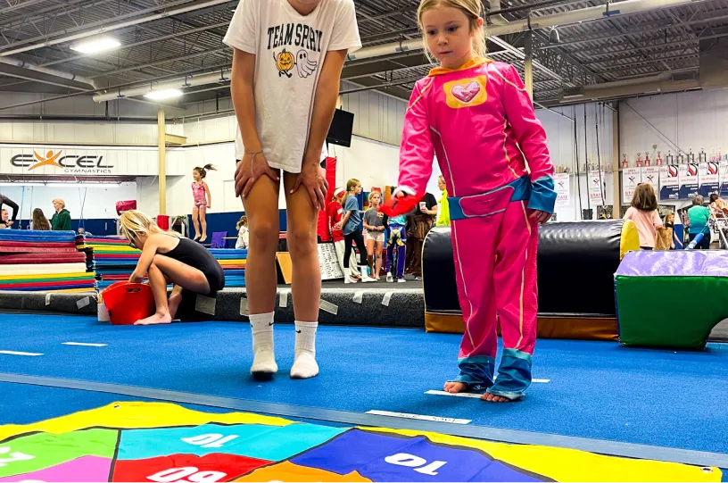 This image shows children participating in a gymnastics activity at Excel Gymnastics Academy.
